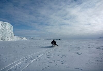 Researcher on snowmobile riding out into a vast snowlandscape in Svalbard