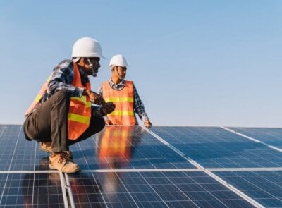 To arbeidere som står på et solcelle-panel
