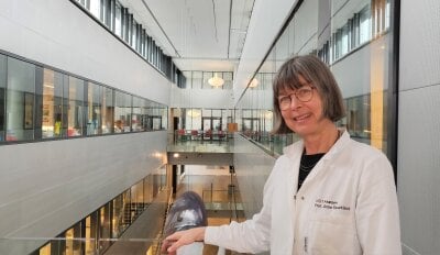 Kvinnelig forsker i hvit labfrakk står i en  trapp