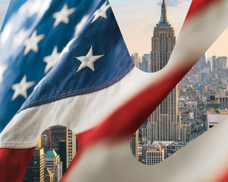 Utsikt over New York City med Empire State Building, sett gjennom et amerikansk flagg i forgrunnen.