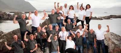 Gruppe av mennesker som viser sterke armer på et berg med utsikt ut en fjord